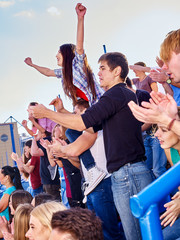 Sport fans hands up and singing  on tribunes.