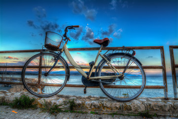 Fototapeta na wymiar old bike on a railing by the sea