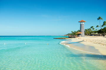 Paradise Caribbean landscape. Clear sea, white sand, tropical palm trees and lighthouse on sandy shore