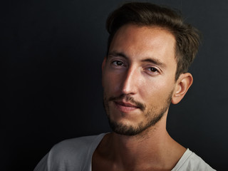 Portrait of handsome young man wearing white tshirt on the black background . Horizontal