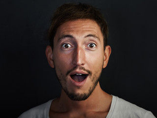 Portrait of handsome young man wearing white tshirt and looks surprised. Horizontal