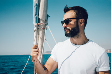 Portrait of young bearded man standing on a yacht and looking at the horizon