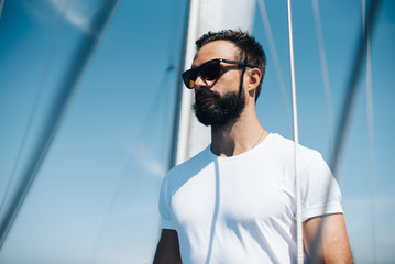 Bearded man standing on a yacht and looking at the horizon.