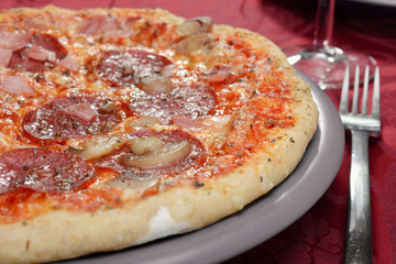 Pizza mit Salami und Pilzen als Mahlzeit beim Italiener oder Pizzeria 