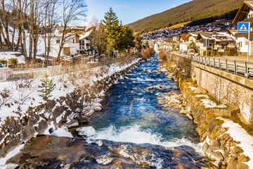 Fototapeta na wymiar river through snowy alpine village