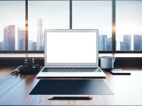 Generic laptop on the workspace with panoramic windows.  City at sunrise in a background. 3D rendering