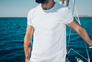 Photo of young bearded man standing on a yacht and looking at the horizon