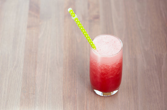 A glass of fresh watermelon smoothie on wooden background