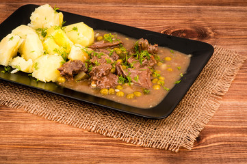 Venison Goulash with potatoes on the black plate.