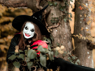 Cute girl dressed to Halloween costume in dark forest