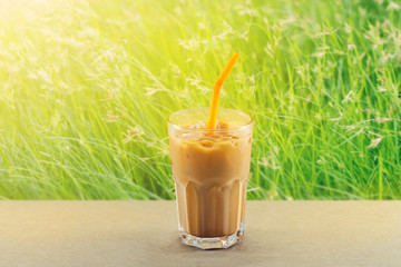 ice tea with milk in glass on grass vibrant nature background
