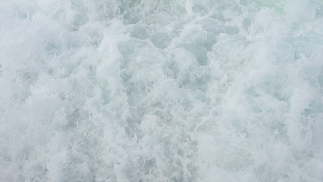 Sea water splashes at the back of a boat, halfway slowed down from 50p to 25p