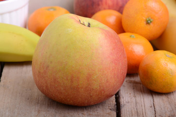 Bananas apple mandarin peach strawberry on wooden background as health food concept