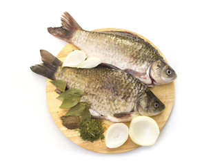 Fresh carp on a cutting board with spices and onions