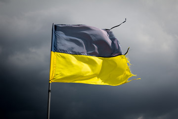 Torn Ukrainian flag on the background of a stormy sky