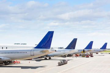 Tails of some airplanes at airport during boarding operation - obrazy, fototapety, plakaty