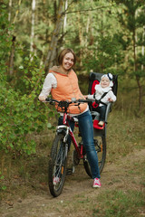 Fototapeta na wymiar mother and daughter riding bike in the forest