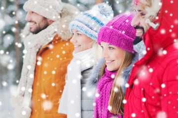 group of smiling men and women in winter forest