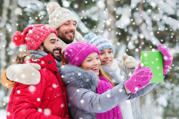 smiling friends with tablet pc in winter forest