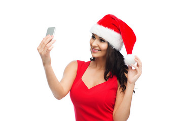 woman in santa hat taking selfie by smartphone