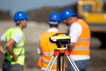 Theodolite and workers at construction site - obrazy, fototapety, plakaty