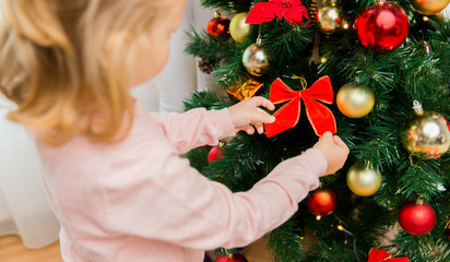 close up of little girl decorating christmas tree