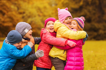 group of happy children hugging in autumn park