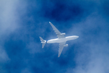 Fototapeta na wymiar Airplane between clouds on a blue sky