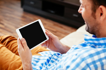 Closeup of digital tablet with blank display held by man relaxing at home