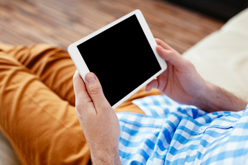 Closeup of digital tablet held by man relaxing at home