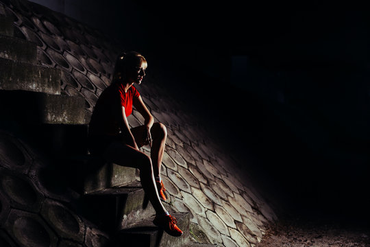 Young Woman Sitting On Stairs At Night After Run