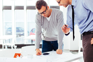 Two architects standing at a desk and discussing a project