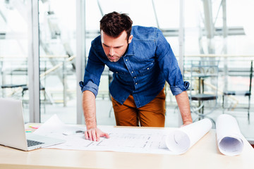 Young architect looking carefully at a  design