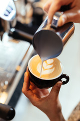 barista pouring milk into art cappuccino or latte