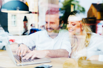 Happy friends meeting at cafe with laptop