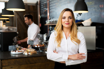 Confident female cafe manager standing at fornt of the bar