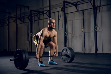 Fototapeta na wymiar Shirtless man lifting barbells at gym