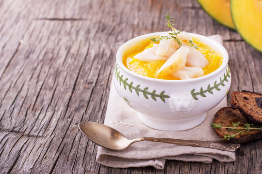 Thick pumpkin soup puree with smoked white fish in portion bowl