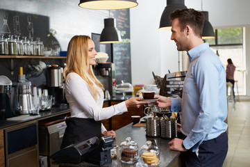 Beautiful barista giving coffee to client