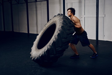 Young man flipping tire at gym