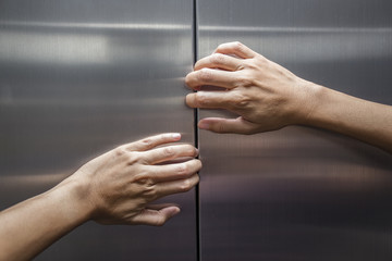 woman hands try to stop doors of the closed elevator