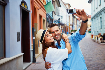 Happy couple of tourists taking selfie in old city