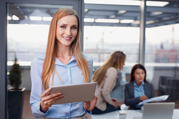Attractive businesswoman at office standing with digital tablet