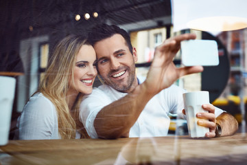 Happy couple at coffee shop taking selfie