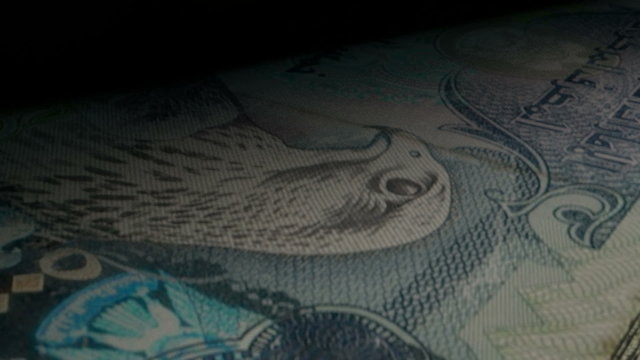 An extreme closeup of dirham flipping through in a counting machine