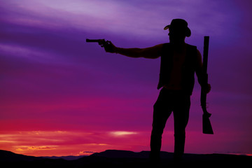 Fototapeta na wymiar silhouette of a cowboy shotgun in hand pistol pointed