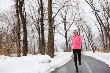 Woman running in snowy city park - winter fitness
