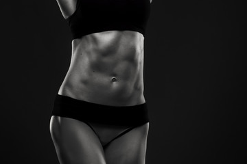 Fototapeta na wymiar Attractive fitness woman on gray background in studio. Muscular abdomen close-up