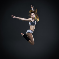 Beautiful young woman dancer jumping in studio
