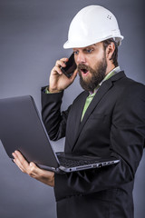 Portrait of a surprised engineer holding his laptop and having a